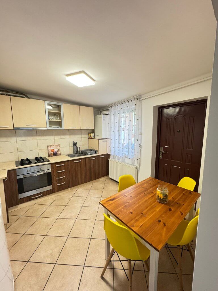 Bucătărie modernă cu mobilier și masă din lemn.